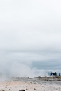 Steam emitting from hot spring against cloudy sky