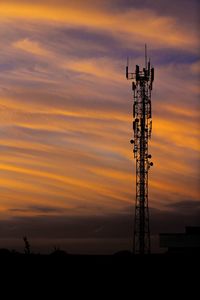 Silhouette of communications tower against sky during sunset