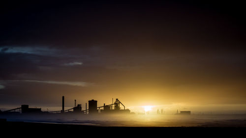 Factory against sky during sunset