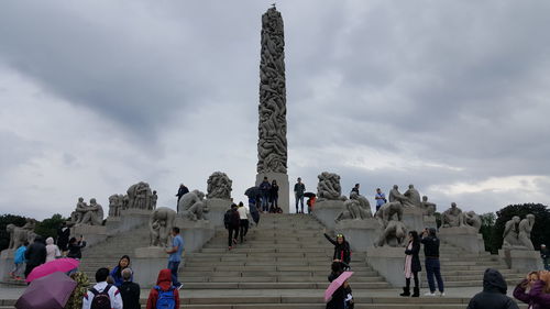 People at town square against cloudy sky