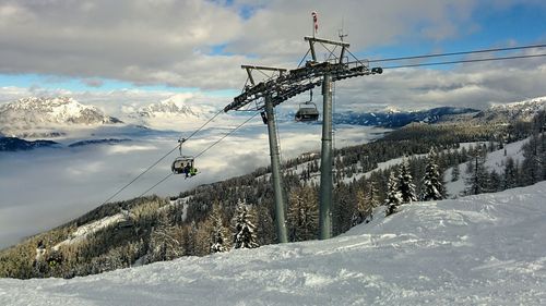 Ski lift on snow covered mountain against sky