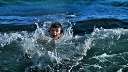 Young man splashing water in sea