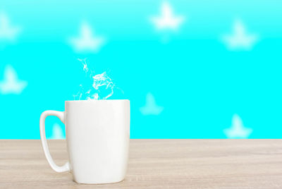 Close-up of coffee cup on table against blue wall