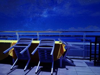 Furniture at observation point against sky at night