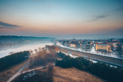 Aerial view of river by buildings in city during sunset