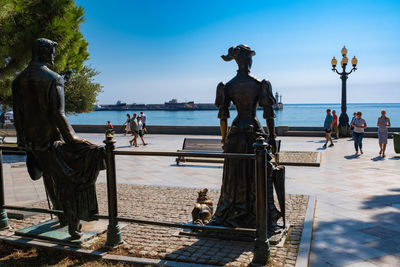 Statue and people at beach against sky