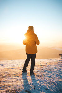 Traveller in a distinctive yellow jacket stands on top of a hill in the polish beskydy