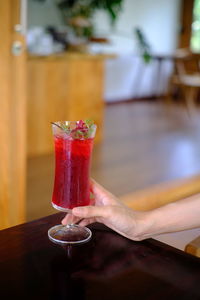 Midsection of woman holding drink on table