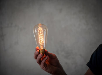 Digital composite image of hand holding illuminated light bulb