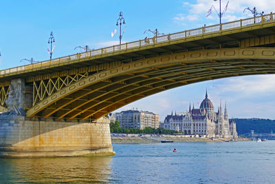 Arch bridge over river against sky in city