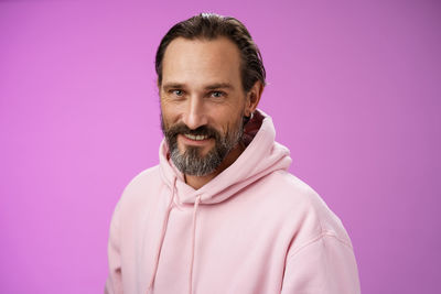 Portrait of smiling man standing against pink background