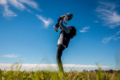 Low angle view of woman playing with girl on grass against sky