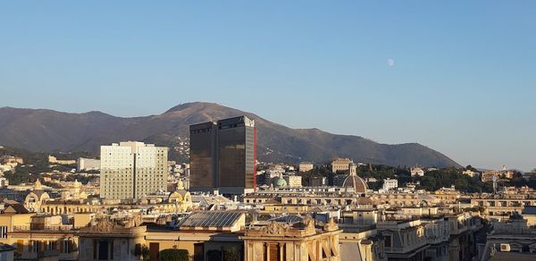 Buildings in city against clear blue sky