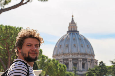 Portrait of smiling young man against historic building