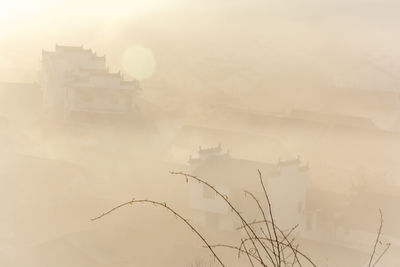 Buildings against sky during foggy weather