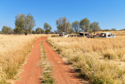 Hay bales on field against clear blue sky