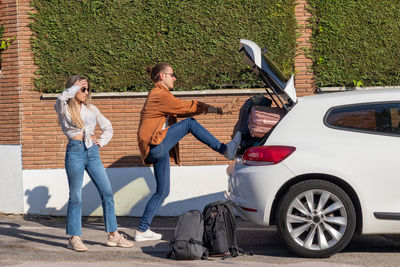 Desperate young couple trying to get all the suitcases in the car to go on road trip in spring break