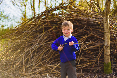 Portrait of cute boy standing against dry plants