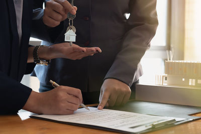 Midsection of man holding paper while standing on table