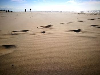 Footprints on sand at beach against sky