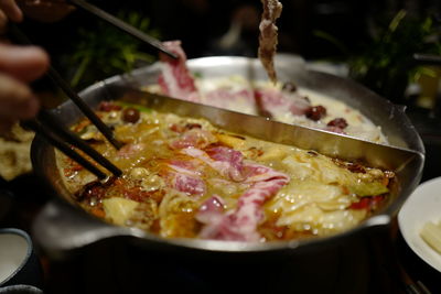 High angle view of hands preparing meat in cooking pan