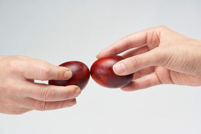 Cropped hand of woman holding fruit against white background