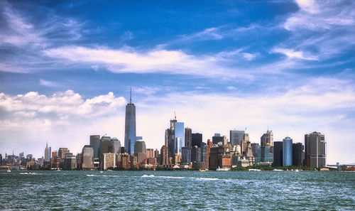 Sea by modern buildings in city against sky
