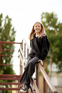 Portrait of young woman standing on railing