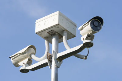 Low angle view of security cameras against sky