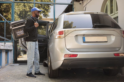 Rear view of man using mobile phone while standing on road