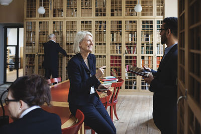 Happy senior lawyer discussing with coworker in board room at library