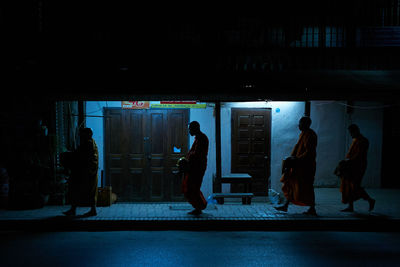 Silhouette people standing in illuminated city at night