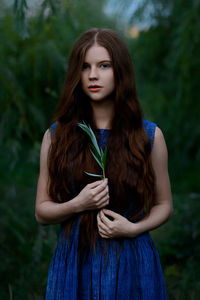 Portrait of young woman standing against plants