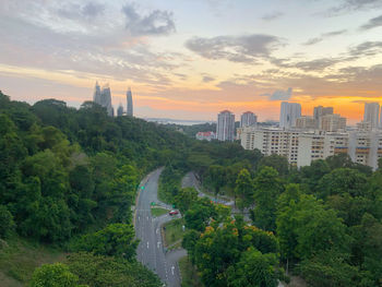 Trees in city against sky during sunset