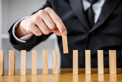 Midsection of businessman playing with dominoes on table