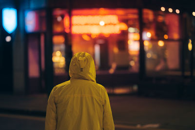 Rear view of woman walking on street at night