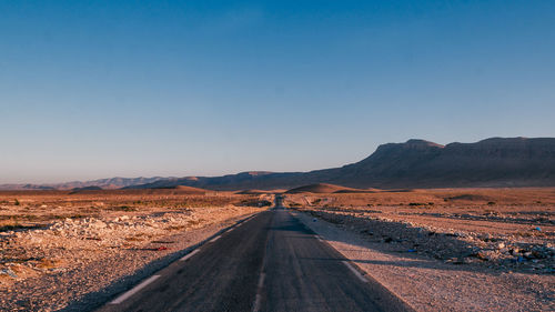 Road amidst desert against clear sky