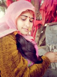 Close-up of young woman against trees