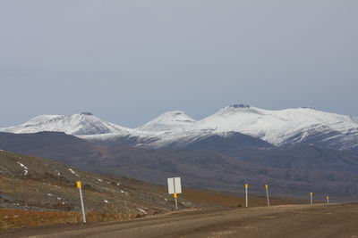 Road leading towards snowcapped mountains against clear sky