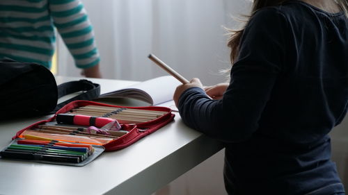 Midsection of girl with pen standing at home