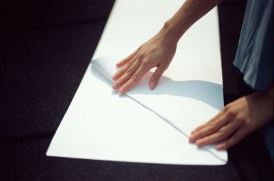 Close-up of hand holding book on table at home