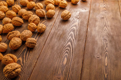 Many walnuts with shells randomly scattered on wooden surface with copy space at the right side