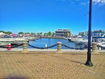 Boats moored at harbor against clear blue sky