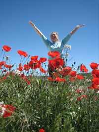 Low angle view of man jumping flower against clear sky