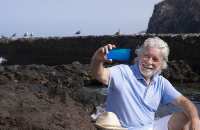 Man using mobile phone against sky