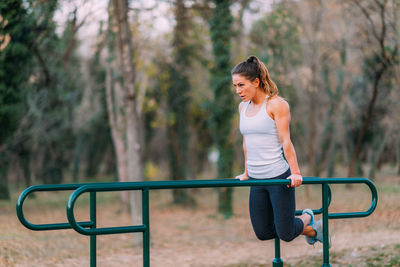 Full length of woman exercising on bars in park