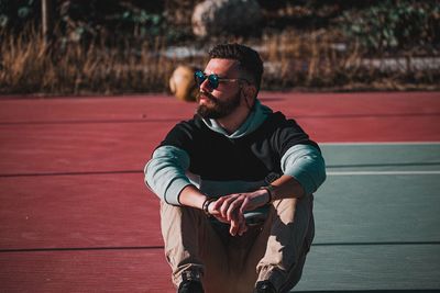 Young man looking away while sitting on sunglasses