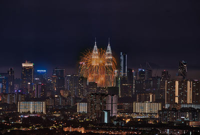 Illuminated modern buildings in city against sky at night