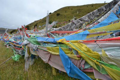 Multi colored flags hanging on clothesline by mountain against sky