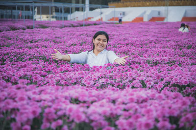 Portrait of woman with purple flowers on field